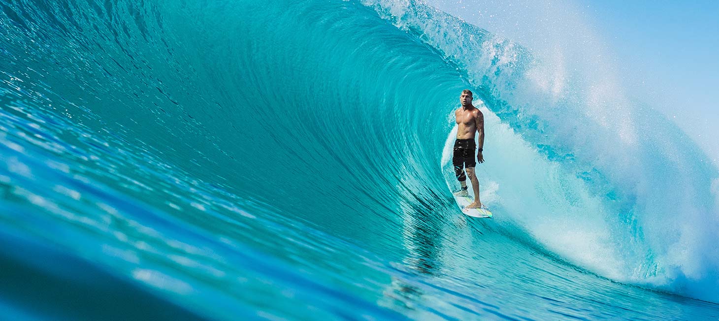 Mick Fanning standing up inside the barrel of a wave. Image links to a video reel avertising the MF1 boardshorts, with highlights of Mick Fanning's stunts 