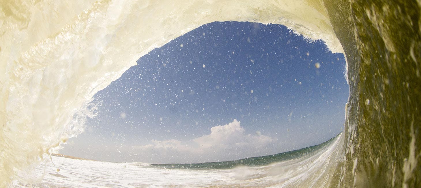 Inside the barrel of a wave, looking out at clear blue skies. Image links to short video about Rip Curl